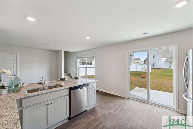 kitchen with light stone countertops, appliances with stainless steel finishes, sink, dark hardwood / wood-style floors, and plenty of natural light