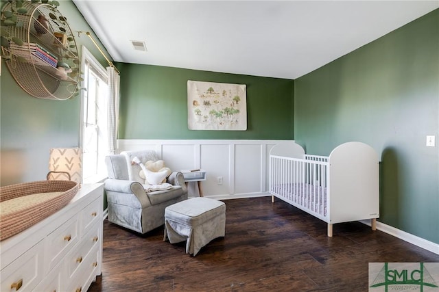 bedroom featuring a crib and dark hardwood / wood-style flooring