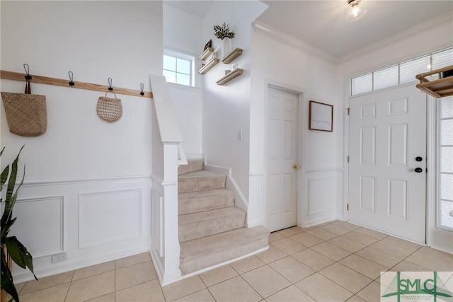 foyer entrance featuring crown molding and light tile patterned flooring