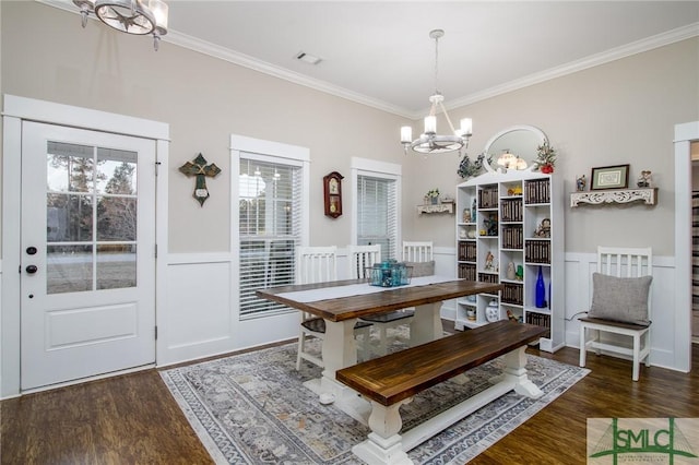 dining room featuring crown molding, dark wood-type flooring, and an inviting chandelier