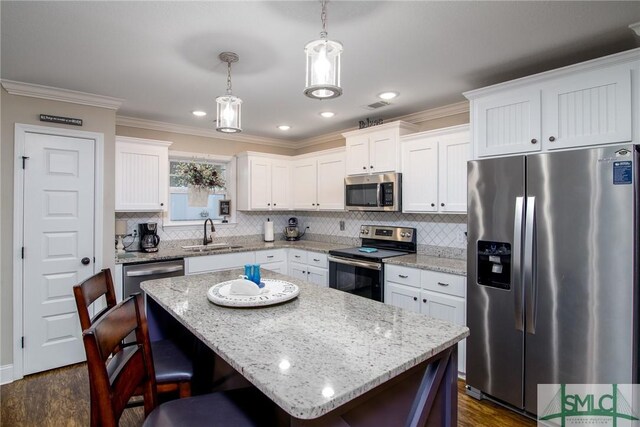 kitchen featuring dark hardwood / wood-style flooring, stainless steel appliances, sink, a center island, and hanging light fixtures