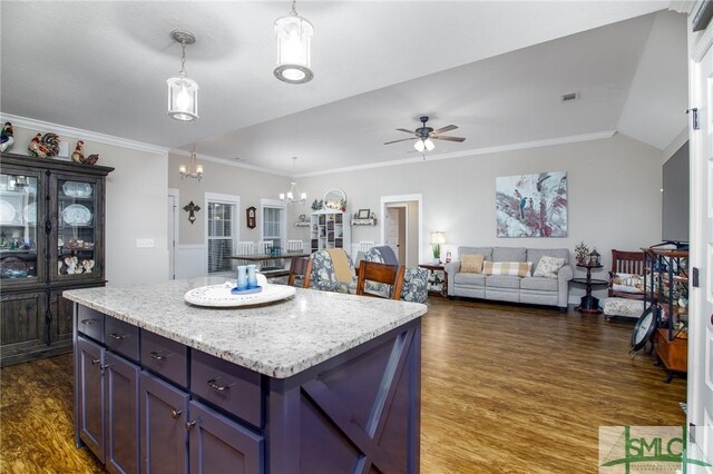 kitchen featuring ceiling fan with notable chandelier, a center island, dark hardwood / wood-style floors, and crown molding