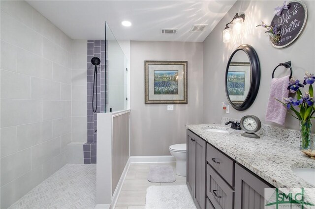 bathroom featuring vanity, toilet, and a tile shower