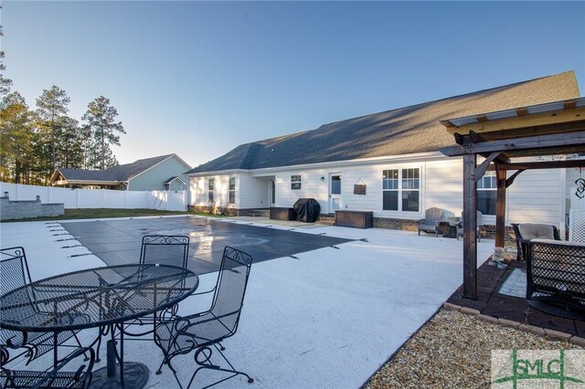 pool at dusk with a patio area and grilling area