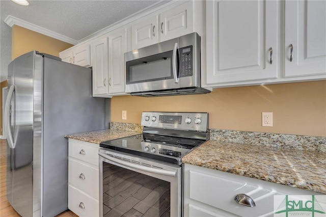 kitchen with white cabinets, a textured ceiling, stainless steel appliances, and ornamental molding