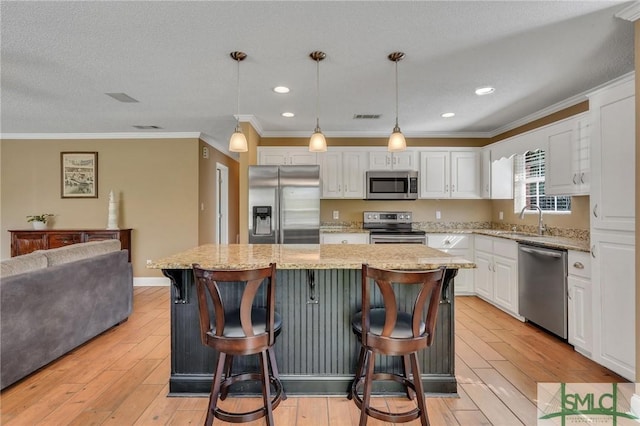 kitchen featuring pendant lighting, a center island, light hardwood / wood-style floors, and appliances with stainless steel finishes