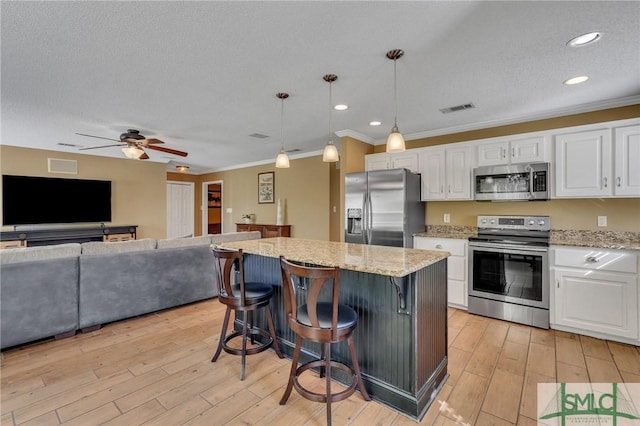 kitchen featuring pendant lighting, a kitchen island, white cabinets, and stainless steel appliances