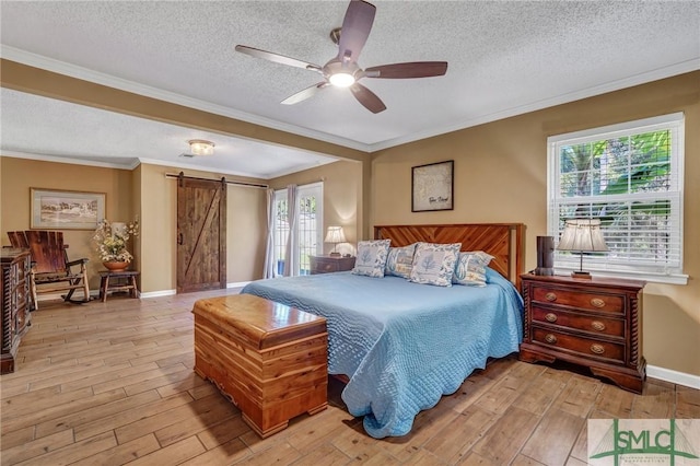 bedroom featuring ceiling fan, a barn door, light hardwood / wood-style floors, a textured ceiling, and ornamental molding