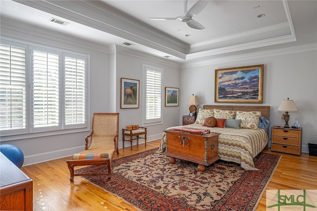 bedroom featuring ceiling fan, light wood-type flooring, crown molding, and a tray ceiling