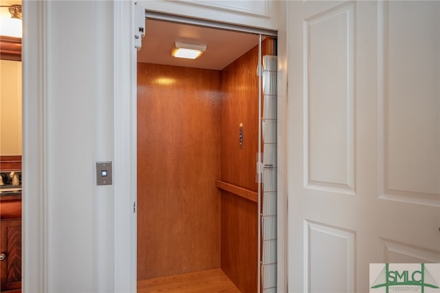 details featuring hardwood / wood-style floors, wood walls, and elevator