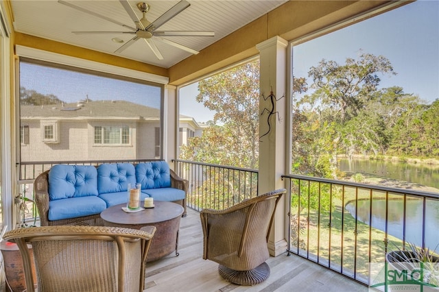 sunroom featuring a water view and ceiling fan