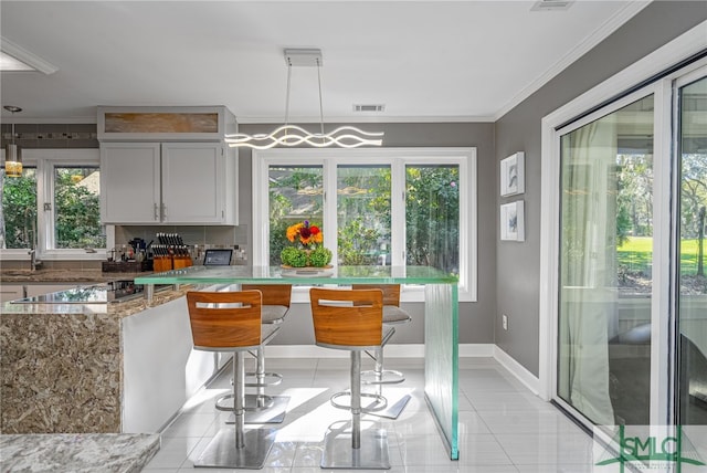 kitchen featuring a breakfast bar, a wealth of natural light, hanging light fixtures, and black electric stovetop