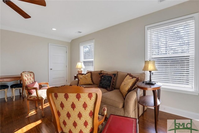 living room with a wealth of natural light, dark wood-type flooring, and ceiling fan