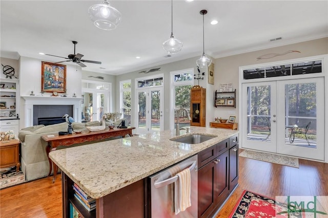 kitchen featuring a center island with sink, decorative light fixtures, light wood-type flooring, and french doors