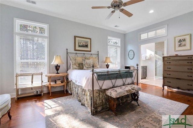 bedroom featuring dark hardwood / wood-style flooring, ensuite bath, multiple windows, and ceiling fan