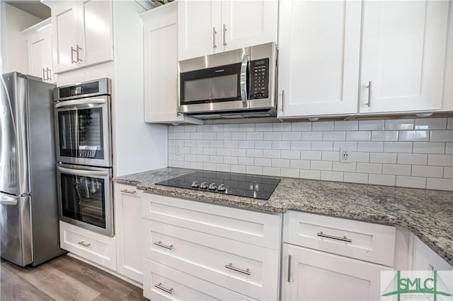 kitchen featuring light stone countertops, tasteful backsplash, stainless steel appliances, white cabinets, and light hardwood / wood-style floors