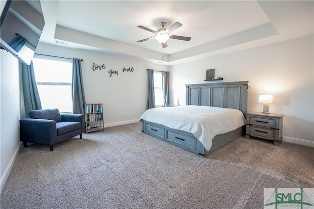 carpeted bedroom featuring ceiling fan and a raised ceiling