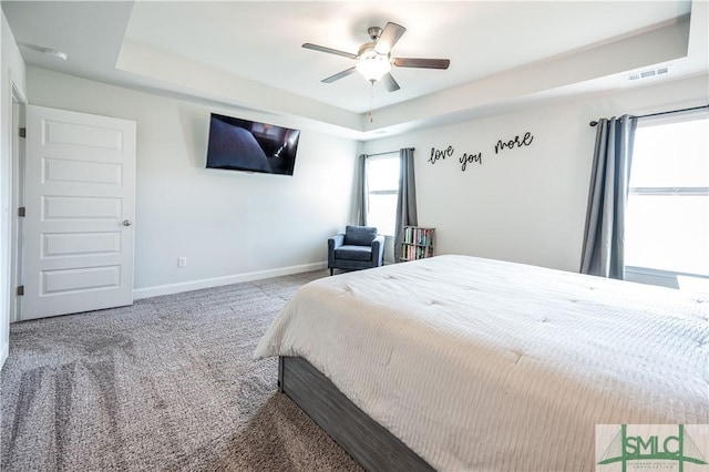 carpeted bedroom with ceiling fan and a tray ceiling