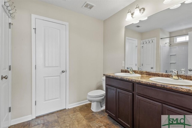 bathroom featuring toilet, a shower, and vanity