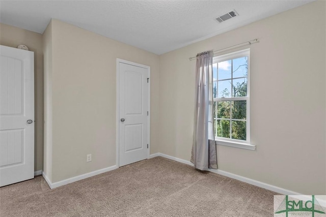 spare room featuring a textured ceiling and light carpet