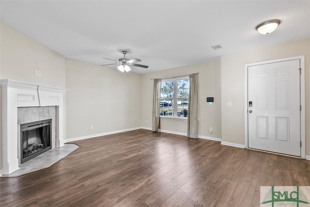 unfurnished living room with ceiling fan, dark wood-type flooring, and a tiled fireplace