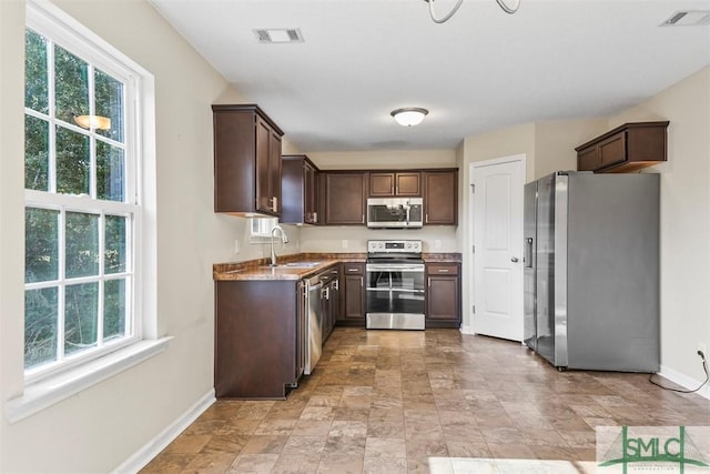 kitchen featuring dark brown cabinetry, stainless steel appliances, a healthy amount of sunlight, and sink