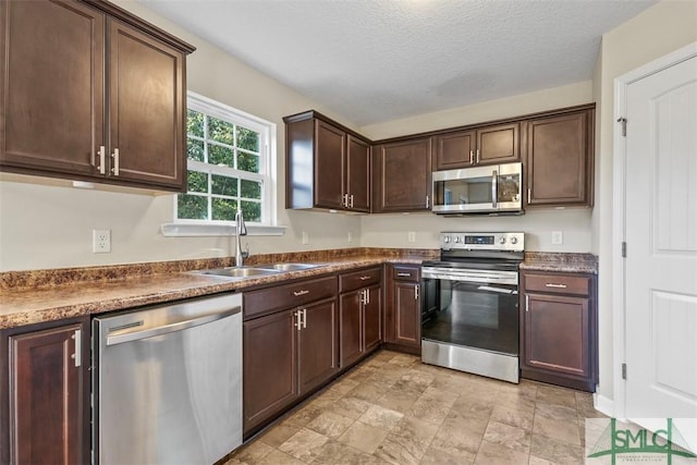 kitchen featuring dark brown cabinetry, sink, stainless steel appliances, and a textured ceiling