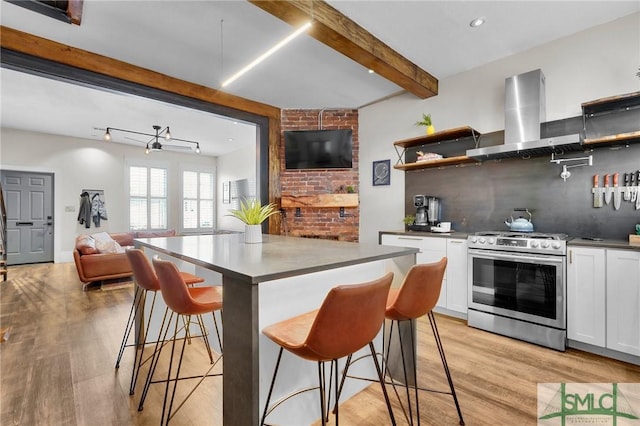 kitchen featuring extractor fan, stainless steel range, white cabinets, a kitchen bar, and beamed ceiling