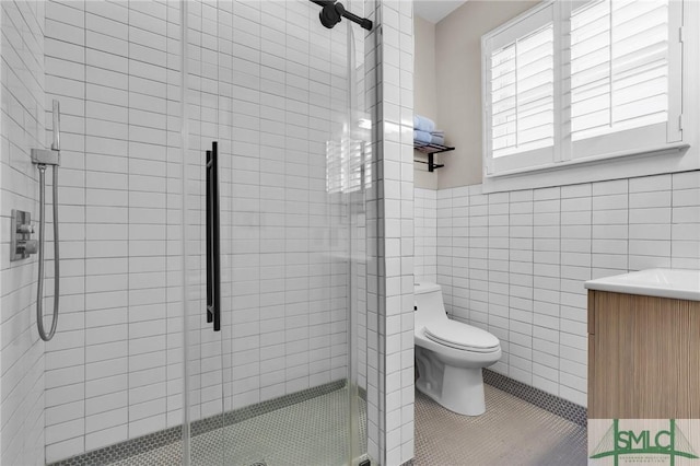 bathroom featuring tile patterned floors, toilet, an enclosed shower, tile walls, and vanity