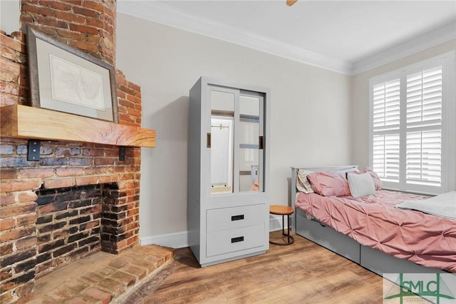 bedroom with crown molding, wood-type flooring, and a brick fireplace