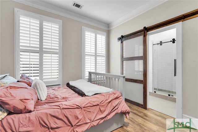 bedroom featuring crown molding, a barn door, and light hardwood / wood-style flooring