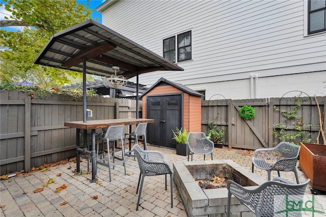 view of patio / terrace with a bar, a storage shed, and a fire pit