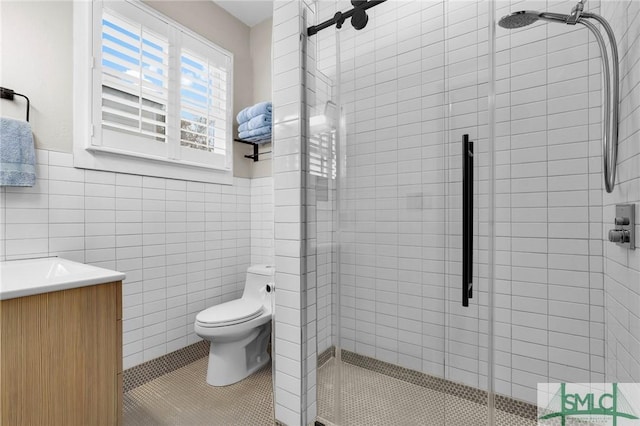 bathroom featuring tile walls, vanity, a shower with shower door, tile patterned floors, and toilet