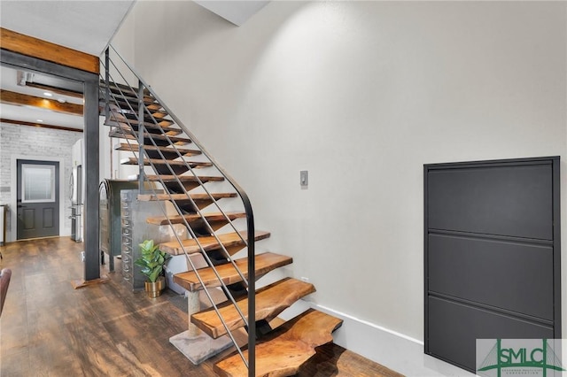 stairway with beamed ceiling and hardwood / wood-style floors