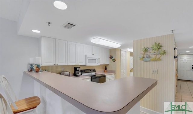 3 3rd St Unit 517, Tybee Island, GA 31328 - kitchen featuring electric range oven, white microwave, a peninsula, light countertops, and recessed lighting