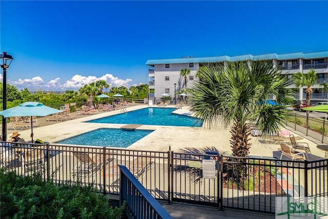community pool with a patio and fence
