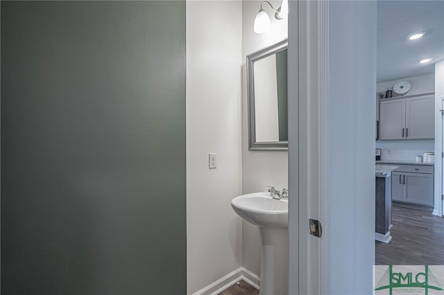 bathroom with hardwood / wood-style flooring, tasteful backsplash, and sink