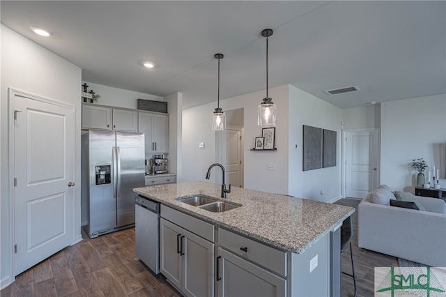 kitchen featuring sink, dark hardwood / wood-style flooring, pendant lighting, a kitchen island with sink, and appliances with stainless steel finishes