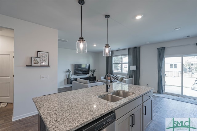 kitchen featuring dark wood-type flooring, sink, a healthy amount of sunlight, and a center island with sink