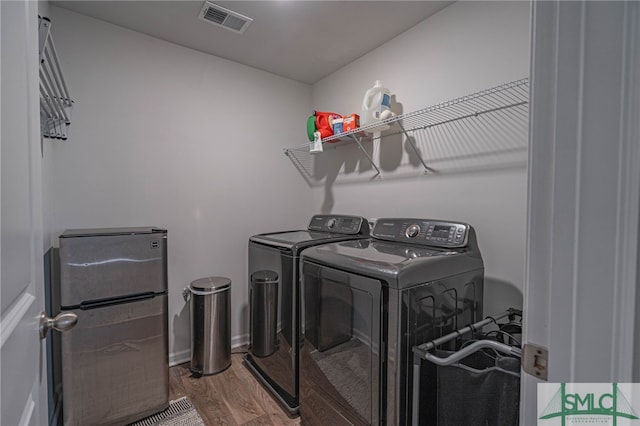 clothes washing area featuring hardwood / wood-style floors and washer and clothes dryer