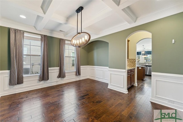 unfurnished dining area featuring dark wood-style floors, beam ceiling, coffered ceiling, and a wainscoted wall