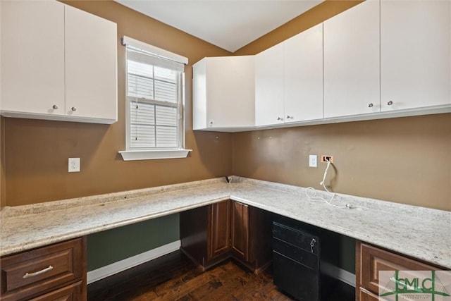 kitchen with dark wood finished floors, built in study area, and white cabinetry