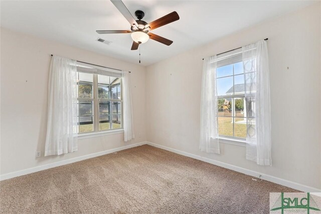 carpeted empty room with ceiling fan, visible vents, and baseboards