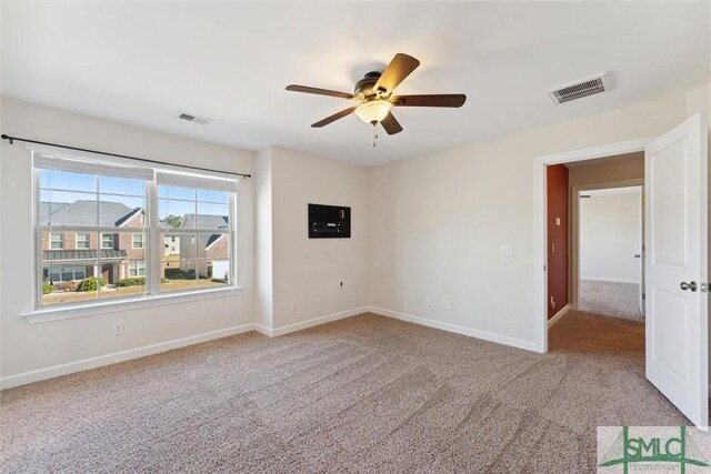 empty room featuring carpet floors, visible vents, ceiling fan, and baseboards