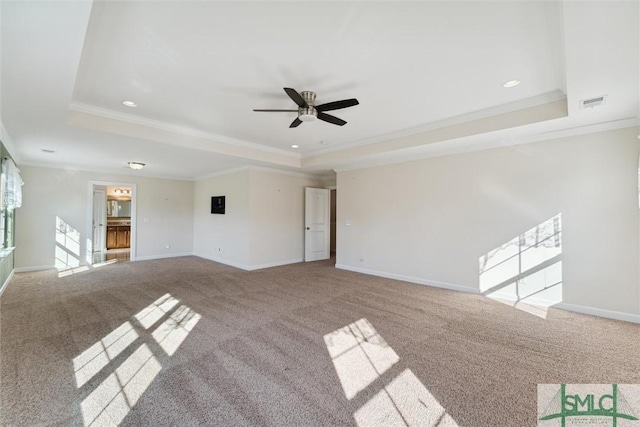 unfurnished living room featuring carpet floors, a raised ceiling, visible vents, ornamental molding, and baseboards