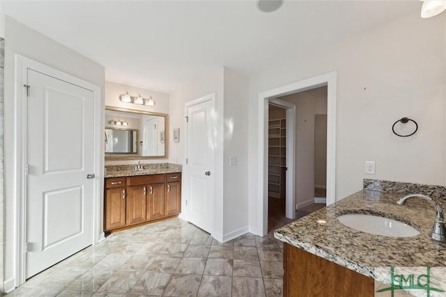 bathroom featuring two vanities, a sink, and baseboards