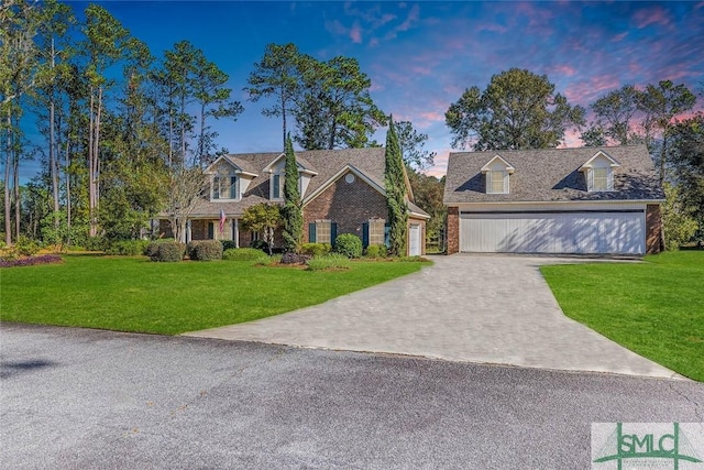 cape cod home with a lawn and a garage