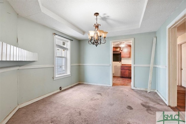 unfurnished dining area featuring a textured ceiling, an inviting chandelier, light colored carpet, and a raised ceiling