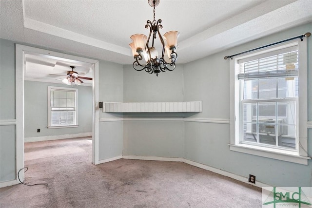 carpeted empty room featuring a textured ceiling, ceiling fan with notable chandelier, a raised ceiling, and plenty of natural light