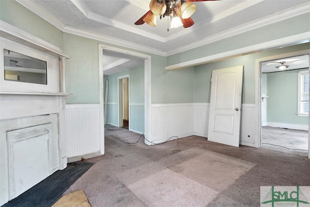 unfurnished living room featuring carpet, ornamental molding, a textured ceiling, and a tray ceiling